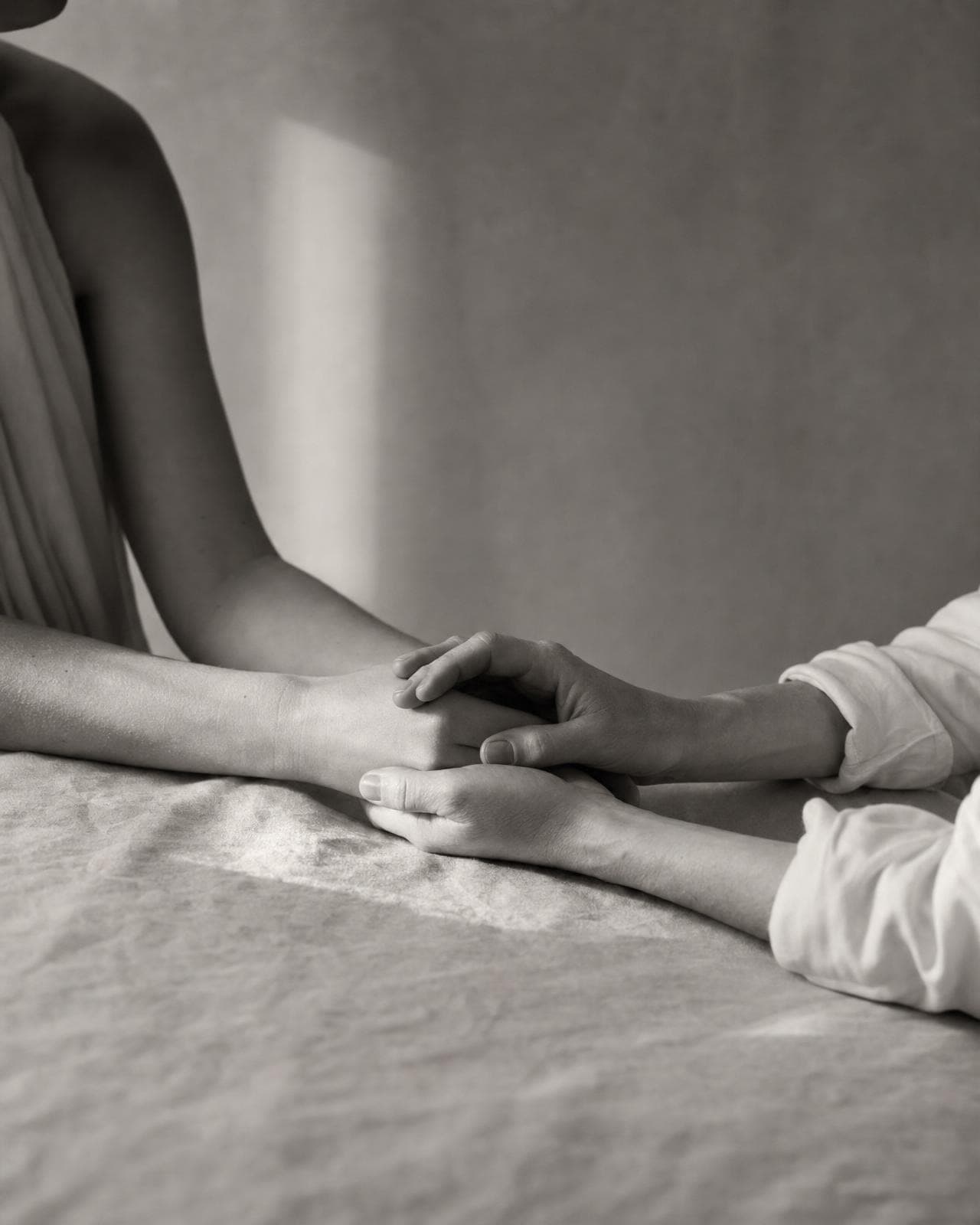 Hands gently clasped across a linen table — patient care and financing at Dr. Kriya's Beverly Hills practice