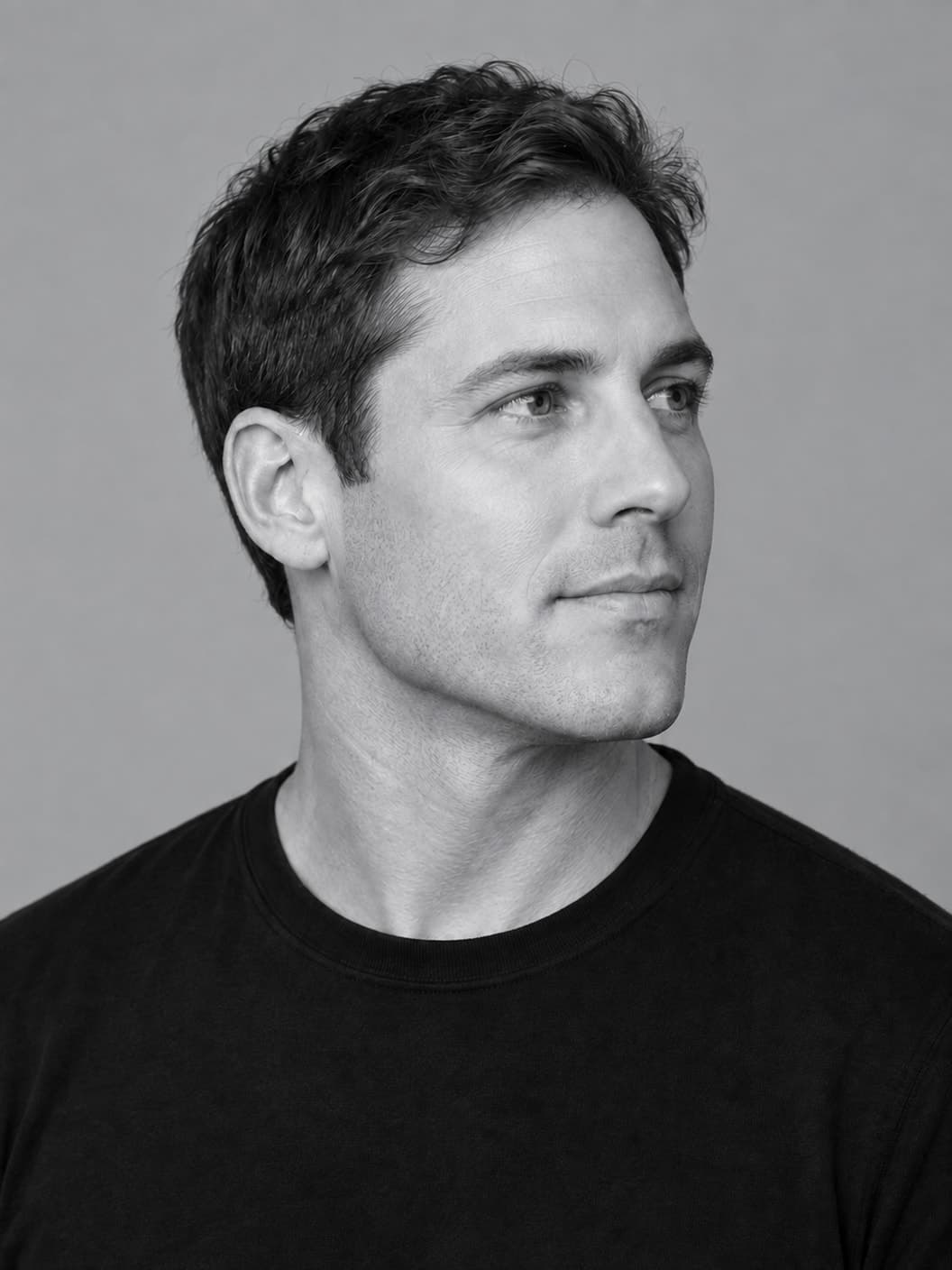 Monochrome three-quarter portrait of a man with his chin and jawline clearly visible against a neutral gray background