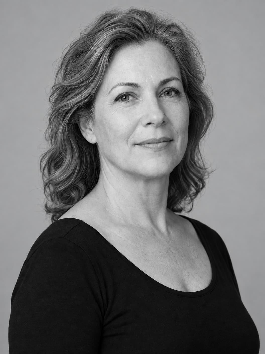 Monochrome portrait of a mature woman showing her face, jawline and neck against a neutral gray background
